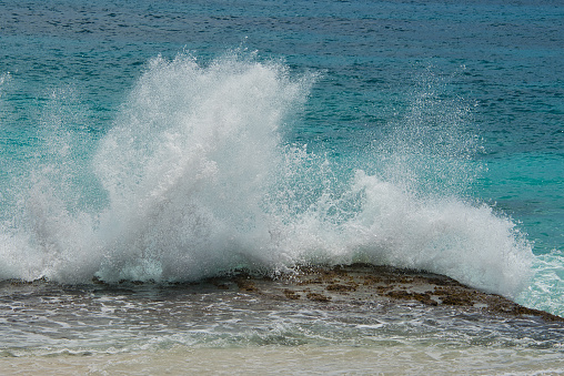 Powerful storm generated ocean swell exploding dangerously on the shoreline with soft golden sky