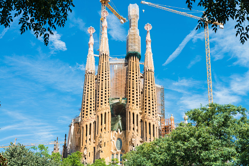 Barcelona, Catalonia, Spain - September 16th, 2013: Sagrada Familia Cathedral designed by famous architect Gaudi under blue summer sky with construction cranes, building up the cathedral towers. Catalonia, Barcelona, Spain, Europe