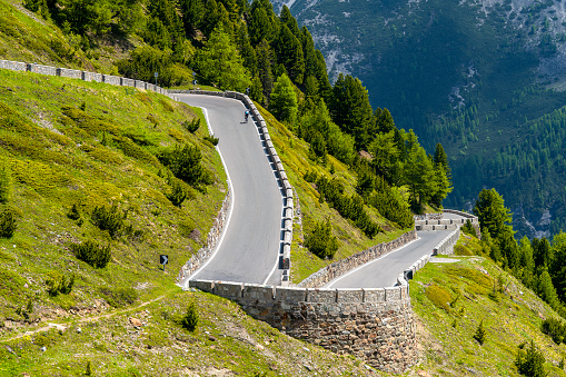 Hairpin bend on the classic climb of the Stelvio Pass, Italy, with a cyclist climbing. Famous climb of the Giro d'Italia.
