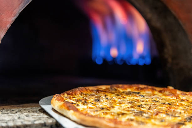 istock Mixed pizza fresh from the pizza oven with flames visible in the background 2014639818