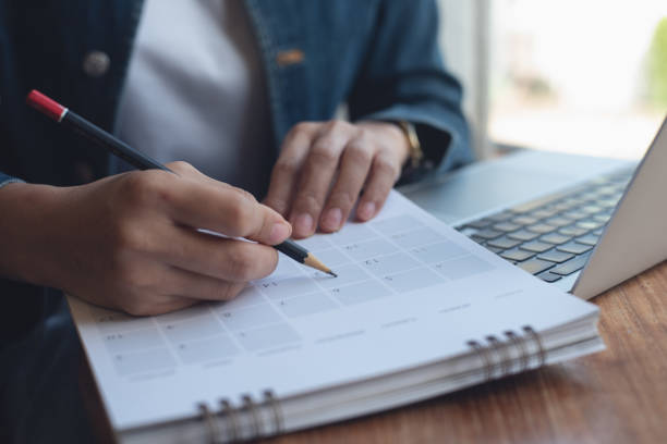 istock 2024 Event planner timetable agenda plan on schedule event. Business woman checking planner, taking note on calendar desk on office table. Calendar event plan, work planning 2014642214
