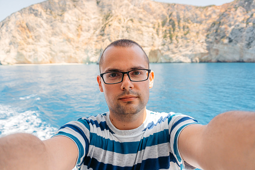 Young man taking selfies on the boat in Parga in Greece. Personal perspective.