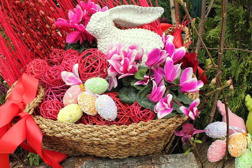 White bunny, flowers, ribbons and eggs on rattan basket decor on streets of the city. Easter decor in rustic style. Easter holiday decoration of the central square. Happy Easter concept