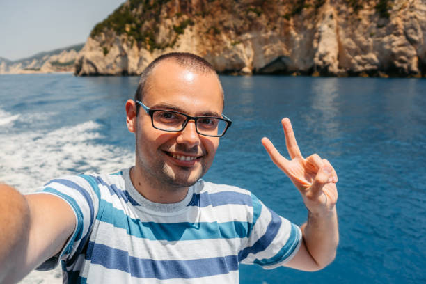 Young man taking selfies on the boat in Parga in Greece. Personal perspective.