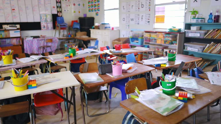 Class, school and education or empty room in kindergarten with reading books, pencils or learning. Desk, chairs and kids development or study for lesson or child care facility, knowledge or teach