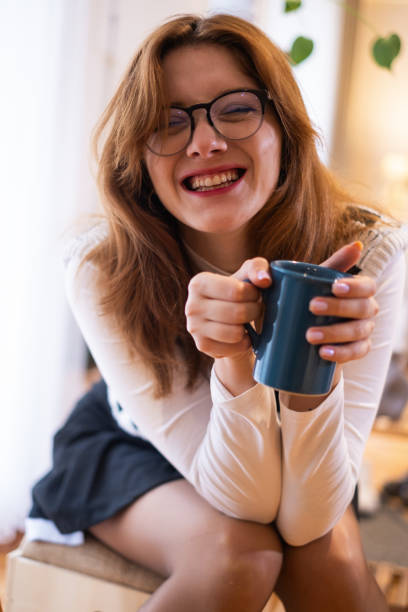 Cheerful woman enjoying coffee cup at home in afternoon.