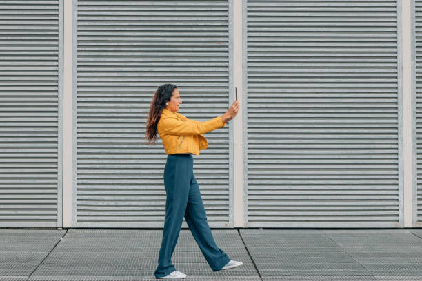 istock woman walking looking at mobile phone or smartphone 2014712002