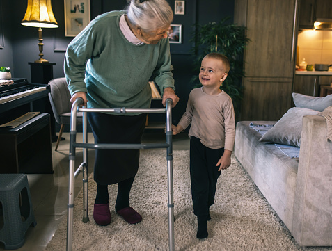 an elderly woman with a disability spends time with her grandchild at home