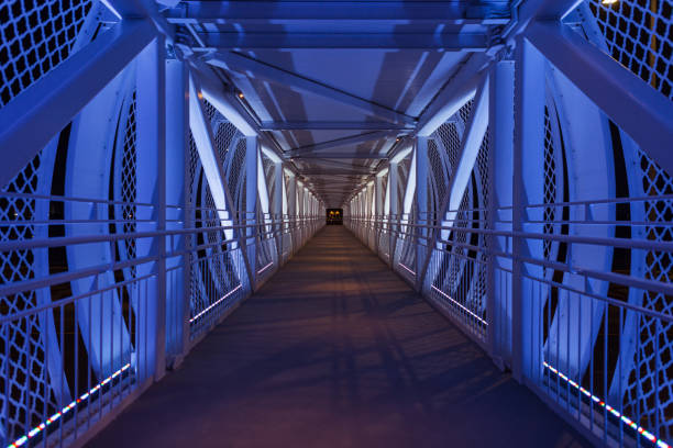 Beautiful foot bridge with blue colored lights at night. Path along the bridge. Transition