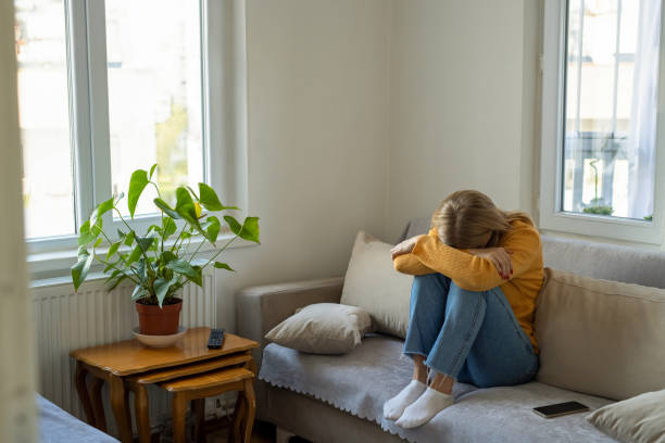 Sad woman sitting on sofa at home
