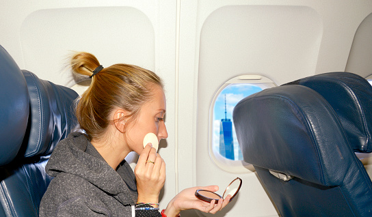 Young woman make up  in airplane before landing in NYC
