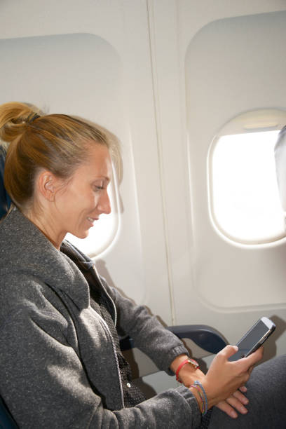 istock Young woman looking phone  in airplane 2014744214