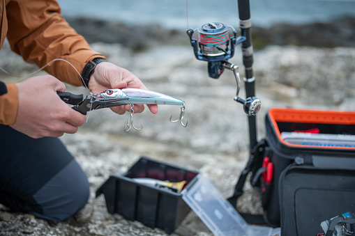 Close-up of man preparing fishing lures for shore fishing.He is getting ready for casting.