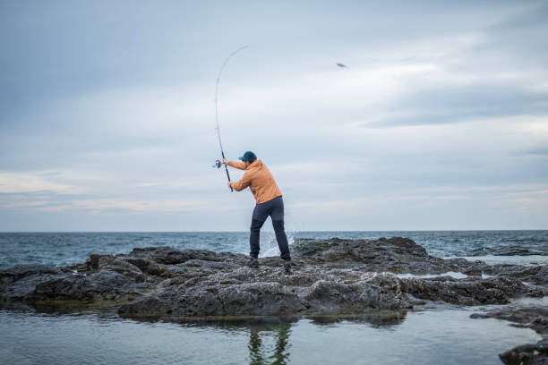 istock Fisherman casting at a shore fishing. 2014753816