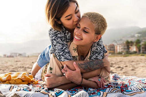 Beautiful multiethnic lesbian couple of lovers dating outdoors - LGBT people bonding and spending time together, concepts about LGBTQ community, diversity, love and lifestyle