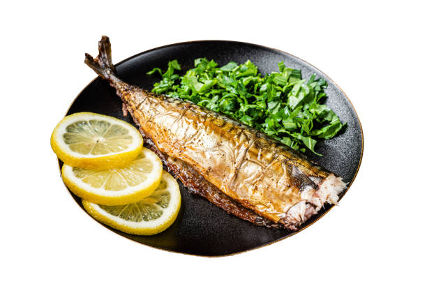 Grilled Mackerel Scomber fish on a plate with greens and lemon.  Isolated on white background.  Top view