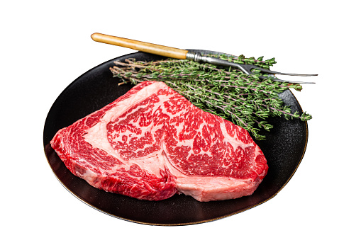 Black Angus Rib Eye steak, raw marbled beef meat with herbs.  Isolated on white background.  Top view