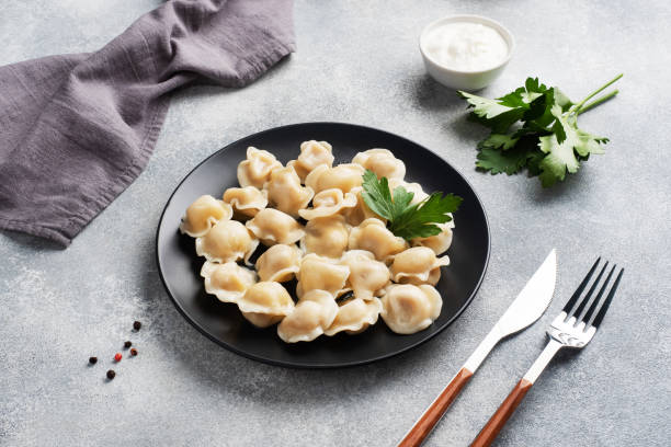 Traditional pelmeni, ravioli, dumplings filled with meat on plate, russian kitchen. Light concrete background, copy space. Traditional pelmeni, ravioli, dumplings filled with meat on plate, russian kitchen. Light concrete background, copy space russian pelmeni stock pictures, royalty-free photos & images