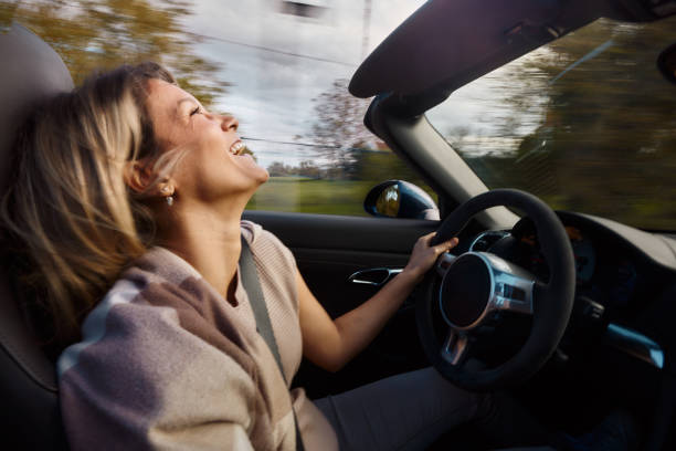 istock Cheerful woman having fun while driving a convertible car in blurred motion. 2014911978
