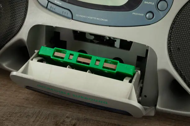 Green magnetic cassette tape in recorder, retro analog music downloaden from radiostation in the 90's.  Listening to cassette music is making a comeback .