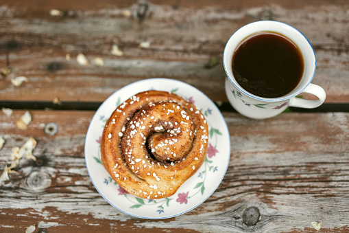 Top view of a cup of coffee and plate with cinnamon roll