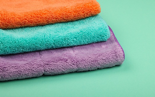 Stack of several new soft colorful microfiber clothes and mops for household cleaning, high angle view, close up
