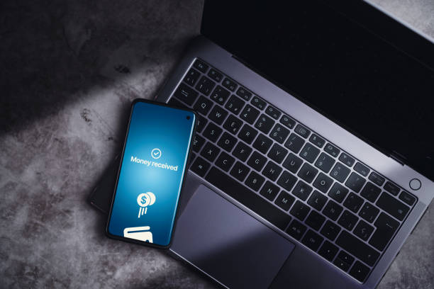 istock Smartphone resting on laptop with money transferred online on screen. 2015000333