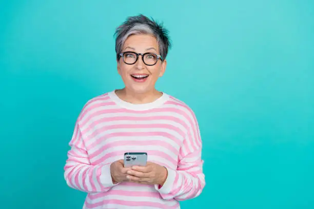 Photo of funny impressed woman dressed pink pullover communicating modern gadget empty space isolated teal color background.