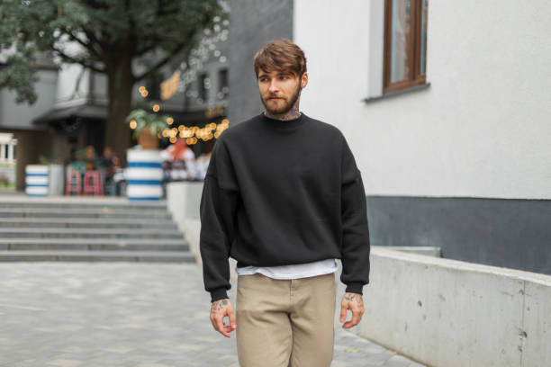 istock Fashionable handsome hipster man with a beard and tattoo in a black stylish mockup pullover walks in the city 2015004686