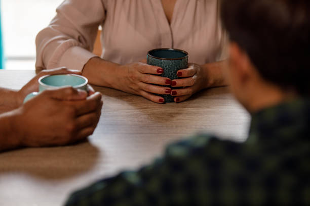 Cheerful couple stands together in their kitchen, each holding white cup of tea, enjoying relaxed morning at home.