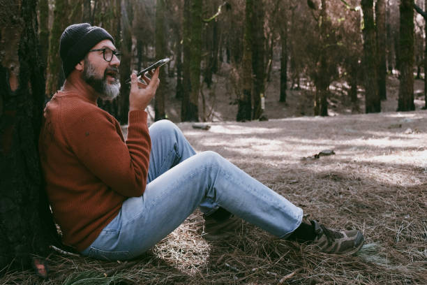 istock One man using phone cellular connection in a forest wood enjoying technology and outdoor leisure activity. Modern man speaking at cellular with trees in background. People and communication on travel 2015014514