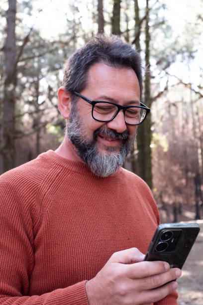 istock One man using phone cellular connection in a forest wood enjoying technology and outdoor leisure activity. Modern man speaking at cellular with trees in background. People and communication on travel 2015020028