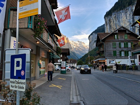 Lauterbrunnen, Switzerland - September 27, 2023: Cars passing on the street in the tourist area of ​​the village and in the background the Swiss Alps