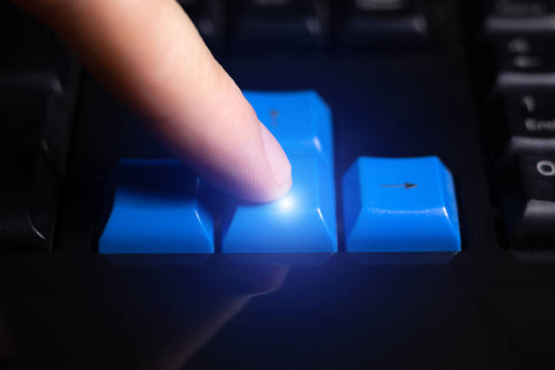 Close-up of finger is pressing computer keys on keyboard during work. Single finger press arrow down button on laptop.