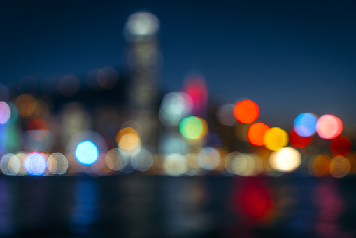 Abstract background featuring out-of-focus city lights reflecting on water at night, creating vibrant bokeh.