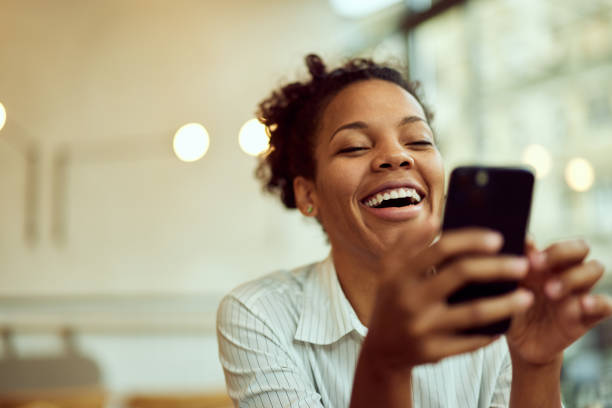 istock Curly-haired African female, using a mobile phone, watching something online, and laughing. 2015033834