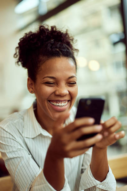istock A beautiful African woman, laughing while using a mobile phone. 2015036101