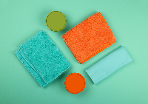 Several new soft colorful microfiber clothes, sponges, mops and household cleaning products, high angle, flat lay, table top view, directly above, close up