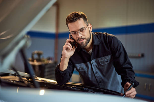 istock A mechanic making a phone call while fixing something on the car in his garage. 2015042061