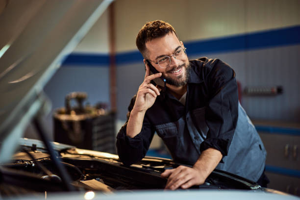 istock A smiling mechanic looking on the side, making a phone call while working at his garage, checking a car. 2015042067