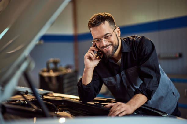 istock Mechanic man checking the car engine while talking to someone over the mobile phone. 2015042071