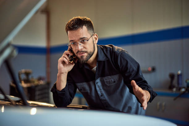 istock A mechanic man is making a phone call while having a car problem at his repair car service. 2015042081