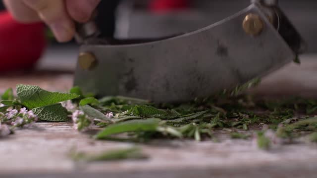 Mezzaluna chopping fresh herbs on cutting board