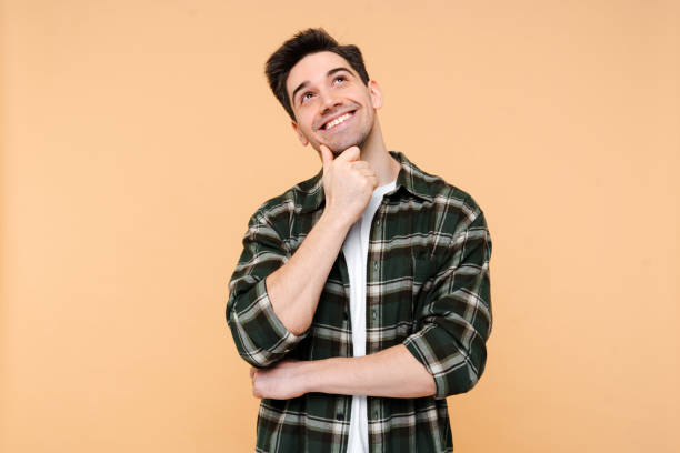 istock Pensive happy man holding hand near face, looking for creative solution isolated 2015076655