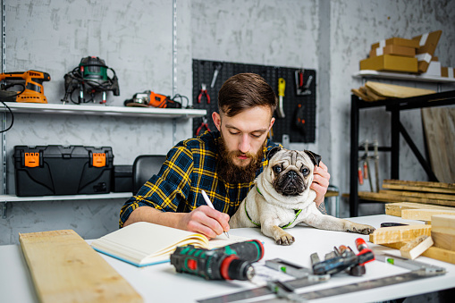Repairman takes notes while holds Pug in lap