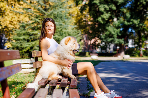 Beautiful woman embraces loving dog on bench in public park