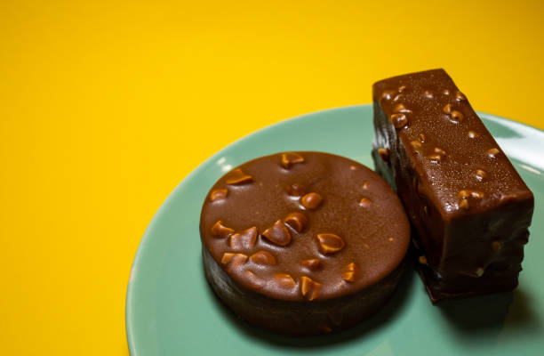 The mousse cake is decorated with chocolate mirror glaze. Modern dessert. yellow background, top view