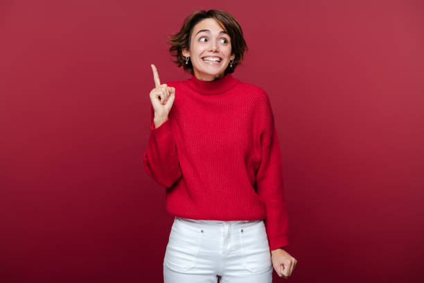 istock Amazed student holding finger up having creative idea isolated on red background 2015097106