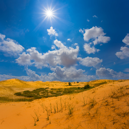 wide sandy desert under blue cloudy sky at summer sunny day