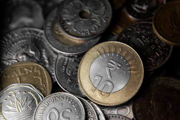 Cutout of pile of money of gold and silver colored metallic currency coins arranged as a neat overlapping set or stack or row of 10 ten rupee denomination coin isolated over white colored transparent background with copy space